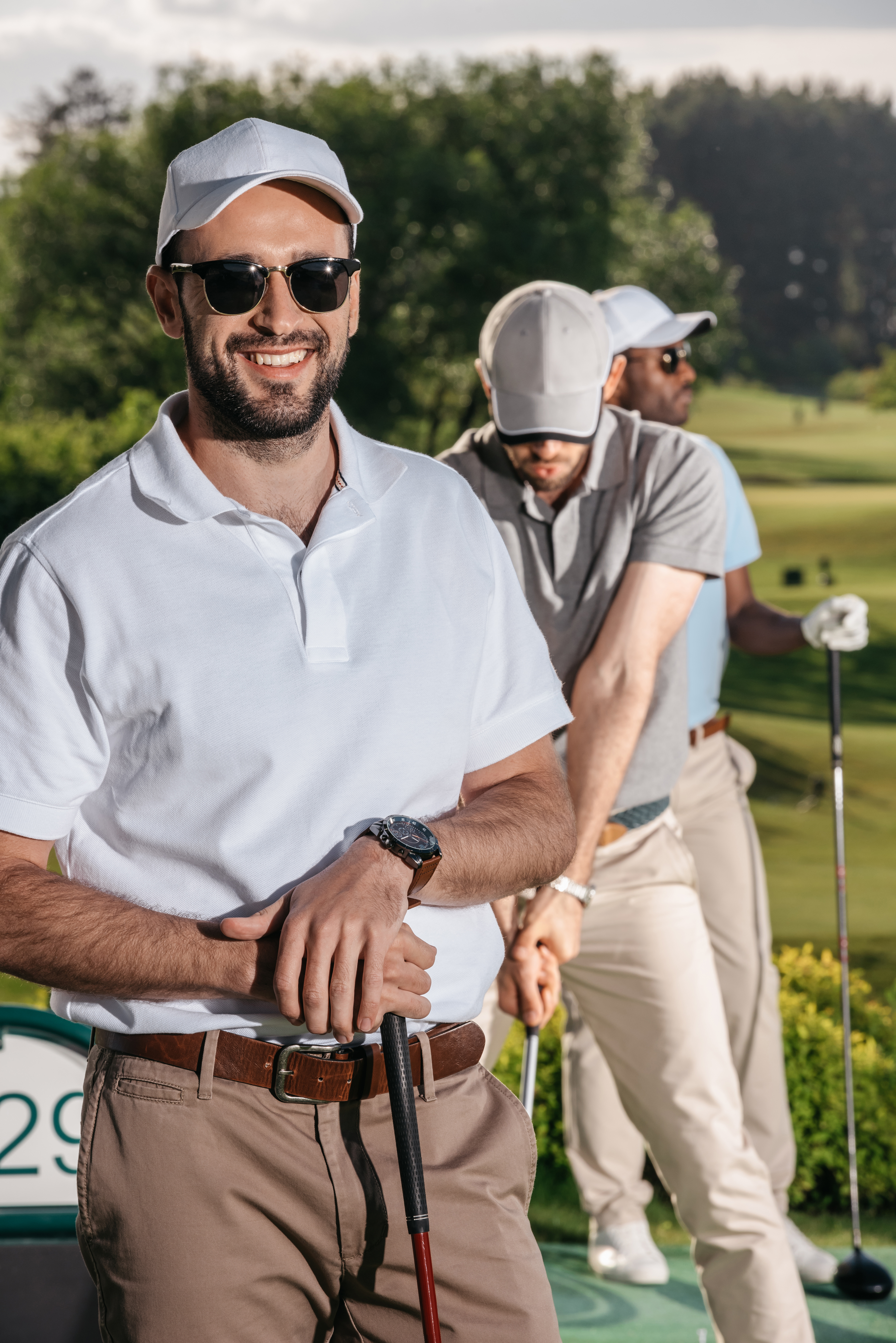 portrait of smiling golfer looking at camera while men playing golf